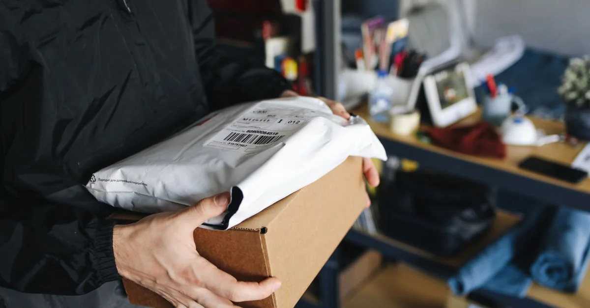 Gros plan sur des mains tenant des colis en carton et en plastique, symbolisant la livraison et l'expédition.